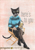 Greeting card of a dressed up cat drinking a beer, text reads here's to you