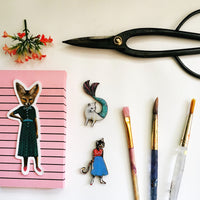 Flat lay of stickers with scissors and paintbrushes. Fox sticker, cat mermaid, cat in a dress Sassy fox laptop sticker, retro dressed up fox sticker, handmade vinyl sticker, fox vinyl sticker www.pergamopapergoods.com