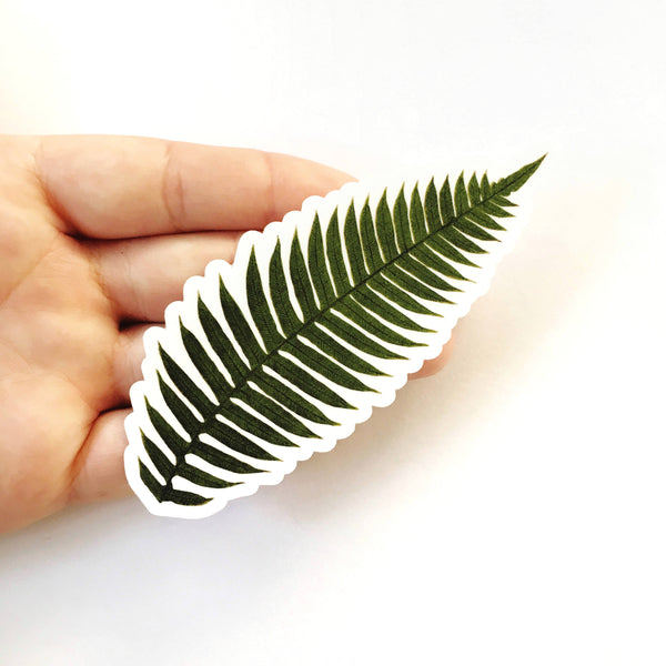 Hand holding fern sticker, naturalistic fern leaf.